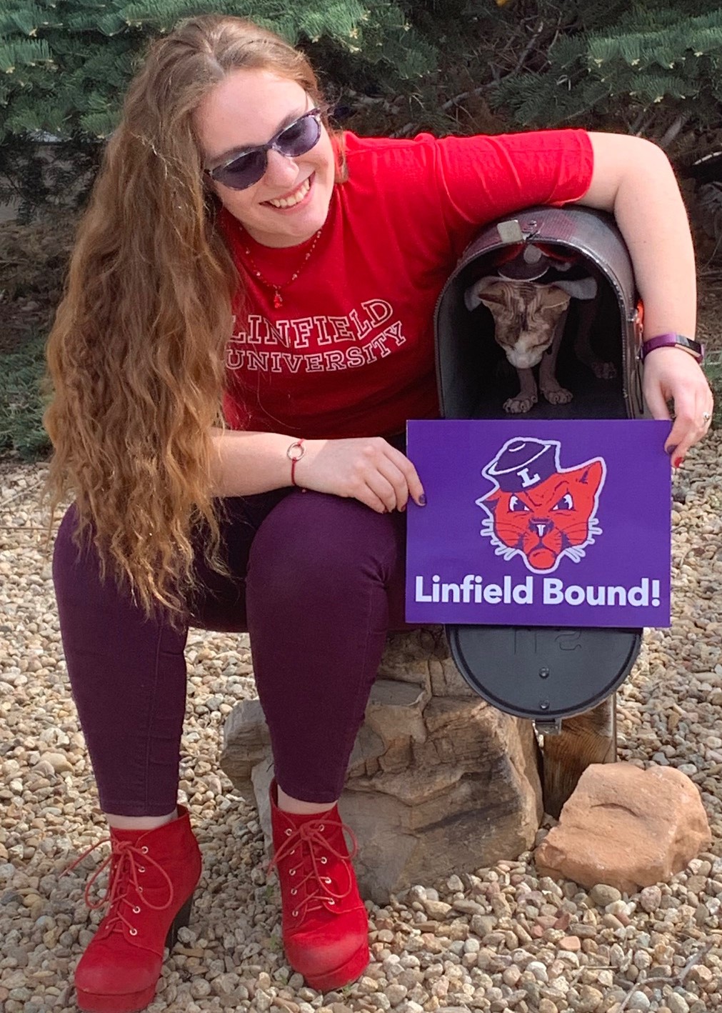 Emberline is wearing a Linfield University shirt holding a Linfield Bound sign. 